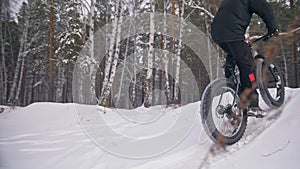 Professional extreme sportsman biker riding a fat bike in outdoors. Cyclist ride in the winter snow forest. Man does