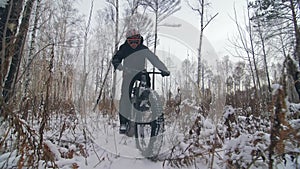 Professional extreme sportsman biker riding a fat bike in outdoors. Cyclist ride in the winter snow forest. Man does