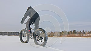 Professional extreme sportsman biker riding a fat bike in outdoors. Cyclist ride in the winter on snow ice. Man does