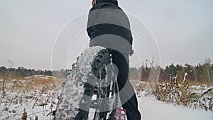 Professional extreme sportsman biker sit a fat bike in outdoor. Cyclist recline in the winter snow forest. Man walk with