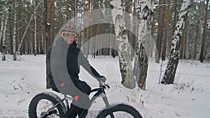 Professional extreme sportsman biker sit a fat bike in outdoor. Cyclist recline in the winter snow forest. Man walk with