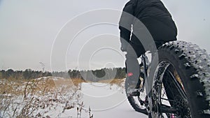 Professional extreme sportsman biker sit a fat bike in outdoor. Cyclist recline in the winter snow forest. Man walk with