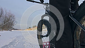 Professional extreme sportsman biker stand a fat bike in outdoor. Cyclist recline in the winter snow forest. Man walk