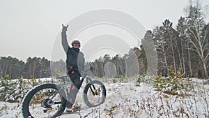 Professional extreme sportsman biker stand a fat bike in outdoor. Cyclist recline in the winter snow forest. Man walk