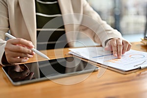 A professional female accountant using tablet and reviewing business financial report at her desk