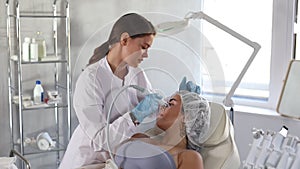 Professional female aesthetician administering hardware procedure on young woman using ion bubble attachment of hydrogen