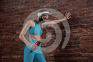 Professional female athlete training on brick wall background wearing face mask. Sport during quarantine