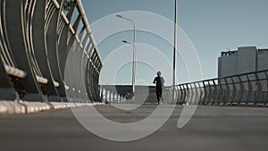 Professional female athlete is training and doing cardio exercises on empty morning city at sunrise. Brunette fitness woman is run