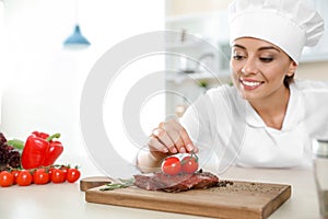 Professional female chef cooking meat on table