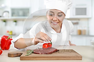 Professional female chef cooking meat on table