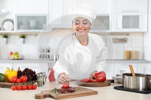 Professional female chef cooking meat on table