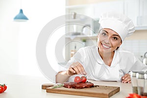 Professional female chef cooking meat on table