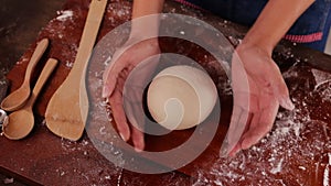Professional female chef prepares dough to make Italian pizza.
