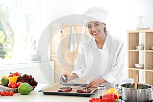 Professional female chef preparing meat on table