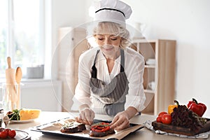 Professional female chef preparing meat on table