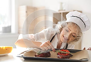 Professional female chef preparing meat on table