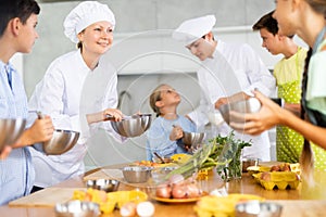 Professional female chef in white uniform conducting culinary class for tweens