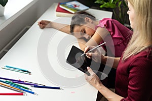 Professional female child psychologist working with a little preschool girl in a bright office. Woman makes notes