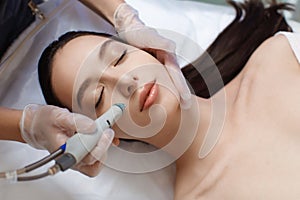 Professional female cosmetologist doing hydrafacial procedure in Cosmetology clinic.