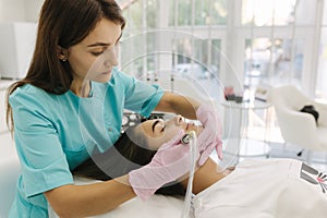 Professional female cosmetologist doing hydrafacial procedure in Cosmetology clinic. Doctor use hydra vacuum cleaner