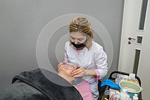 A professional female cosmetologist makes a manual facial massage to a client