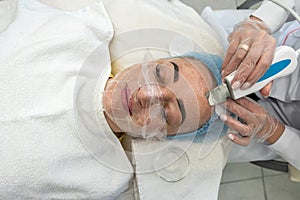 professional female cosmetologist in a mask makes facial contour injections to female patient