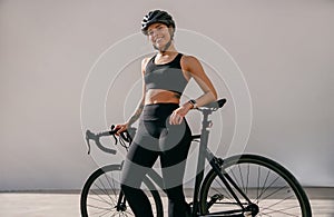 Professional female cyclist in protective gear looking at camera while riding bicycle in city