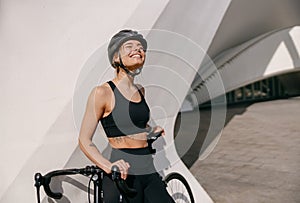 Professional female cyclist in protective gear looking at sun while riding bicycle in city