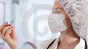 Professional female doctor in hospital room holding disposable syringe. Woman physician at work