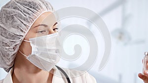 Professional female doctor in hospital room holding disposable syringe. Woman physician at work