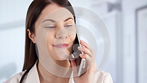 Professional female doctor in hospital room talking on phone with patient. Woman physician at work