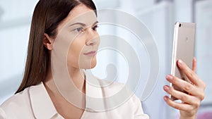 Professional female doctor in hospital room unlocking smart phone. Woman physician at work