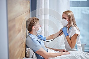 professional female doctor is listening to breath of male patient