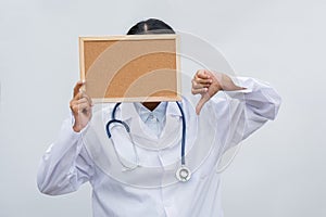 Professional female doctor in white coat over white isolated background and white blank board and Thumbs down. Concept of