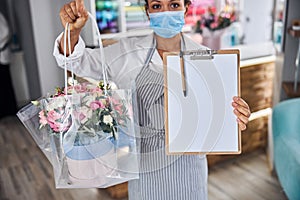 Professional female florist showing a flower bouquet and blank paper