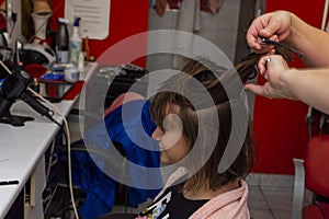 Professional female hairdresser cutting girl& x27;s hair in salon