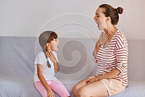 Professional female language therapist working on speech defects with child girl kid having language lesson for improving speaking