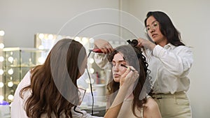 Professional female makeup artist and hairdresser getting ready female to event wedding or meeting. Hairstylist creating