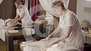Professional female masseur doing massage for client at spa salon, healthcare