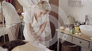 Professional female masseur doing massage for client at spa salon, healthcare
