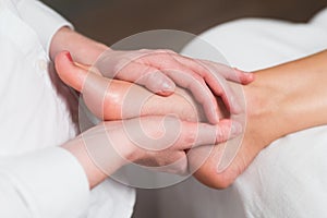 Professional female masseur giving reflexology massage to woman foot