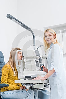 professional female optometrist examining patient through slit lamp