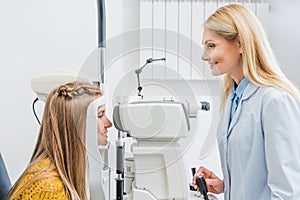 professional female optometrist examining patient through slit lamp