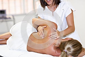 Professional female physiotherapist giving shoulder massage to b