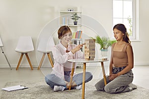 Professional female psychologist during therapy session disclosing teenage girl using jenga game. photo