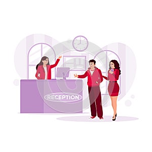 Professional female receptionist serving a pair of guests at the reception desk. Hotel Receptionist concept.