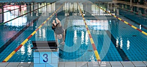 Female swimmer preparing and jumping off the starting block