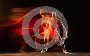 Professional female tennis player isolated on black studio background in mixed light