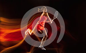Professional female tennis player isolated on black studio background in mixed light