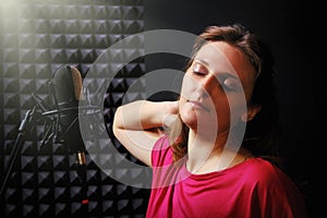 Professional female vocalists in red clothes. Recording a song at the music studio. Woman singing into a microphone on a black